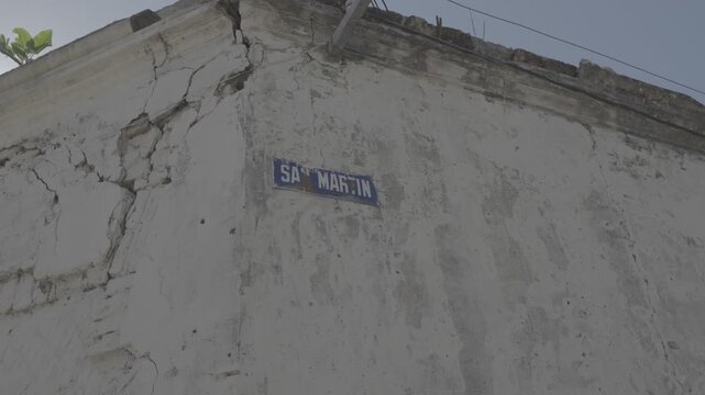 Sunlit cracked stucco wall with a street sign in a small Argentine town