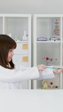 Asian Schoolgirl in Lab Coat Prepares Balloon for Science Experiment