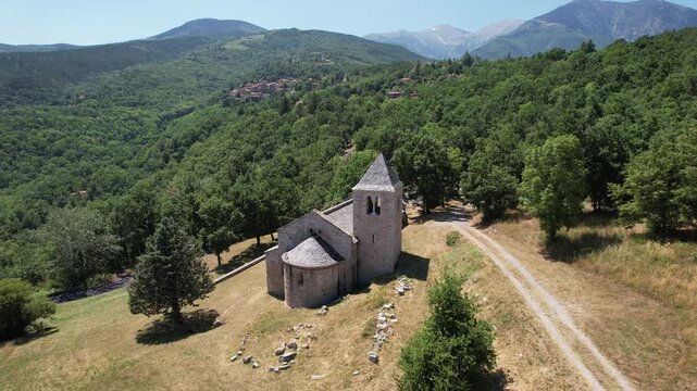 Orbital aerial shot of the Romanesque Chapelle de Sant Marti, an 12th-century stone church nestled in the Pyrenees mountains, Corsavy, France.