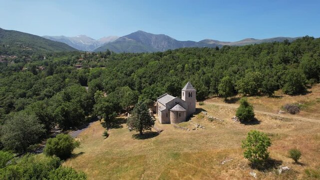 Forward reveal aerial footage of the Romanesque Chapelle de Sant Marti, an 12th-century stone church nestled in the Pyrenees mountains, Corsavy, France.