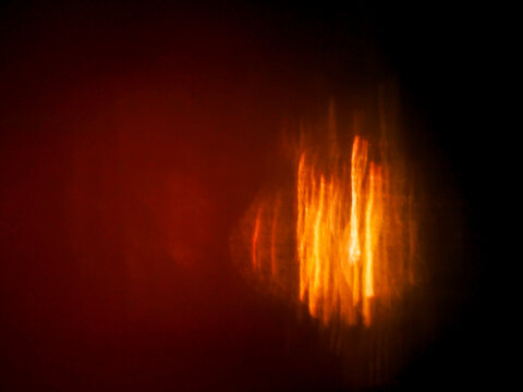 Abstract bokeh background with warm orange and yellow light circles on black. Blurred glowing orbs create soft, dreamy visual effect. Light leaks for design and special effects.