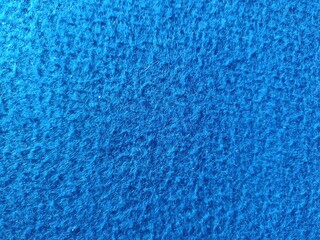 Bright blue felt fabric texture close-up. Soft, fuzzy fibrous textile surface for abstract backgrounds and backdrops. © FebrianiIndah