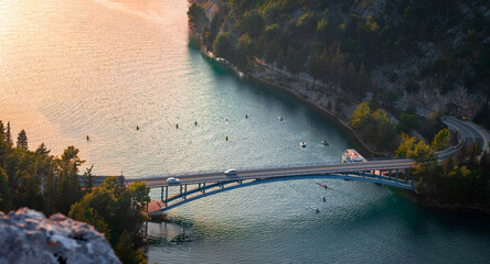 High angle view of bridge over river canyon with cars and rowers in kayaks during sunset © Sonja