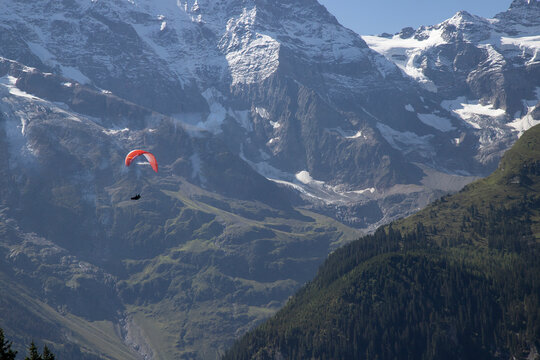 Paraglider flying over mountains in swiss alps