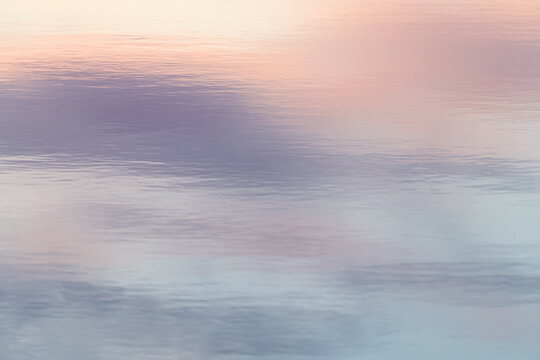 Calm water surface reflecting a pastel sunset sky
