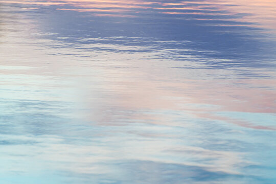 Calm water surface reflects a pastel sunset sky