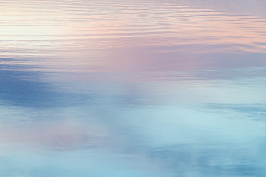 Pastel sky reflection on calm water surface at sunset