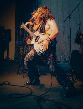 Rock star with long hair plays guitar on stage