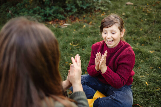 Excited young girl playing a clapping game with her mother