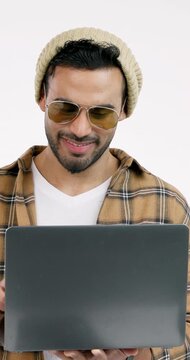 Smile, man and typing in studio with laptop, social media and streaming for latest movie release. Happy, person or laugh with tech, internet search and watchlist of trending video on white background