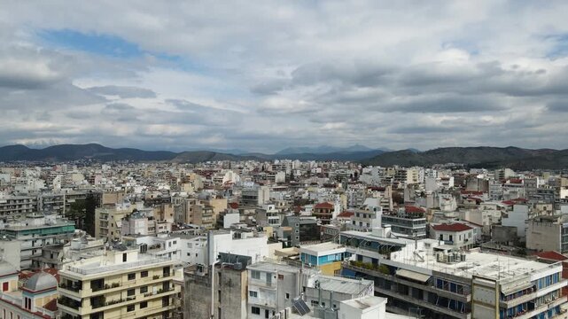 Cityscape of Chalkida showing residential apartment buildings with mountains in the distance under overcast skies. Slow panning shot from left to right reveals the urban density of the Greek town.