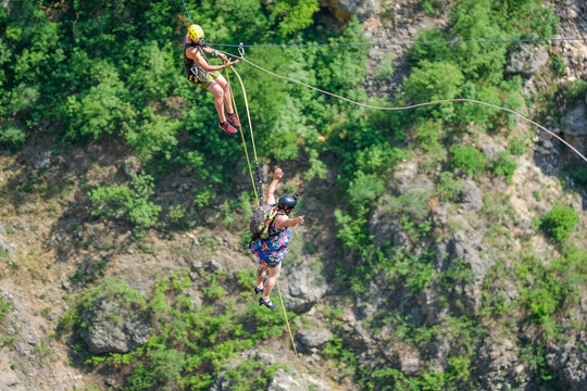 Two people abseiling together down the rock face of the Red Lake karst sinkhole near Imotski, Croatia