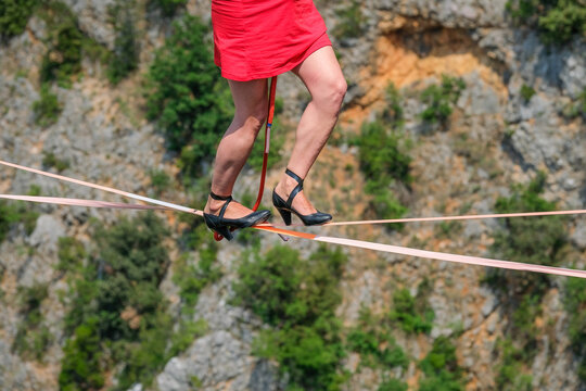 Woman walking a highline in high heels above the Red Lake karst sinkhole near Imotski, Croatia