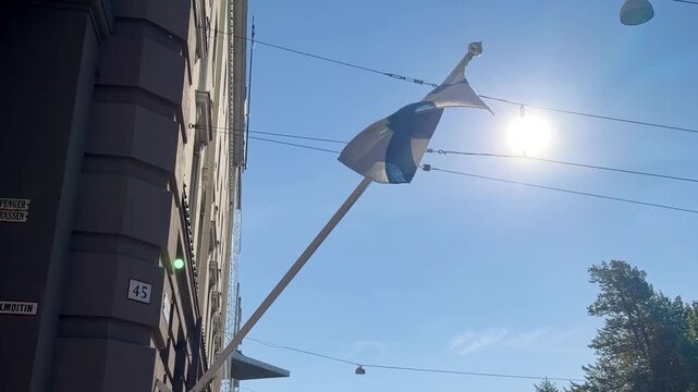 Finnish Flag Waving Against the Sun on a City Street