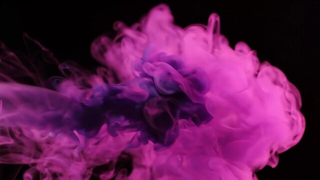 Pink and purple ink clouds billow and expand against a black background. Abstract fluid motion. Color diffusion and pigment mixing. Creative visual backdrop for design and compositing.