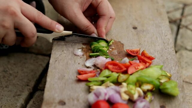 Cutting ingredients such as tomatoes, bilimbi, onions, and chilies to prepare seasoning for traditional Indonesian fish pepes.