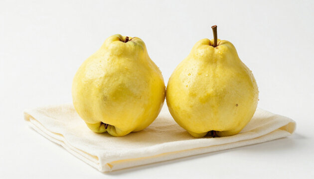Two yellow quinces resting on a folded cotton napkin