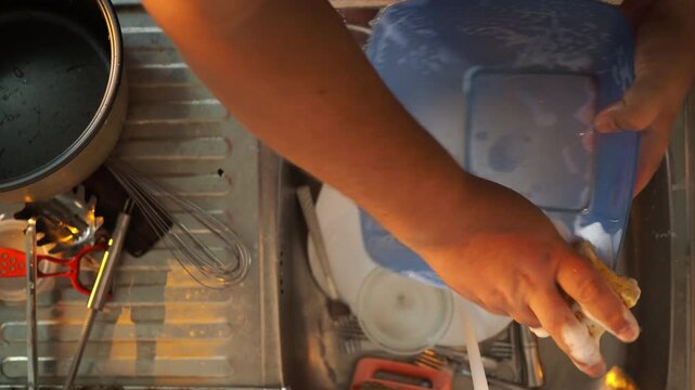 a man washes dishes in a dirty sink
