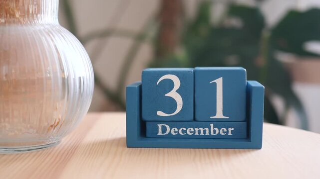 December thirty first wooden block calendar on wooden table with elegant glass vase decor.