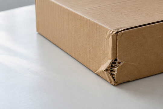 Damaged cardboard box corner on a pale tabletop