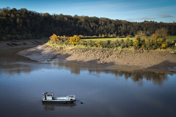 Small boat moored on calm waters of River Wye below Chepstow Castle mudbank in Wales © Chris Jones
