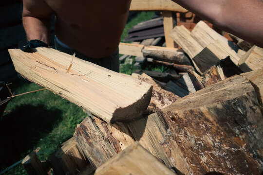 Man loading split firewood into wheelbarrow for winter heating preparation and country house yard work concept