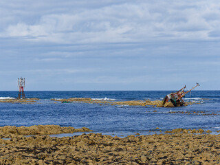 The disintegrating wreck of the Sovereign Fishing Boat on the rocks at Cairnbulg Point Navigation Beacon in Fraserburgh Bay. © Julian