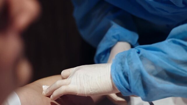 Medical worker preparing patient arm for blood sampling from vein. Close up of venipuncture procedure for laboratory analysis in healthcare setting.