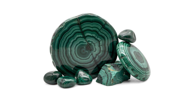 A collection of polished malachite stones and slices showing vibrant green concentric banding patterns isolated on a black background