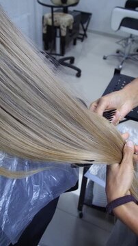 Women's Hair Salon. The stylists at the women's salon are working with a young woman. Beauty salon and makeup - vertical video.