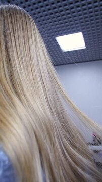 Women's Hair Salon. The stylists at the women's salon are working with a young woman. Beauty salon and makeup - vertical video.