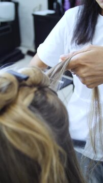 Women's Hair Salon. The stylists at the women's salon are working with a young woman. Beauty salon and makeup - vertical video.