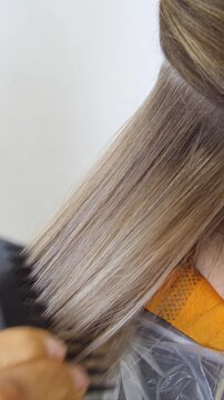 Women's Hair Salon. The stylists at the women's salon are working with a young woman. Beauty salon and makeup - vertical video.