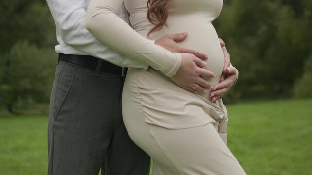 Pregnant woman receives a gentle touch from both parents as their hands rest on her belly creating an intimate family moment filled with love care and anticipation