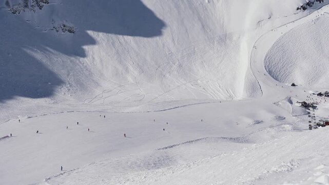 Panoramic view of vast snow mountain landscape revealing bustling ski resort with chair lifts and skiers gliding down slopes, showcasing of a popular winter vacation destination