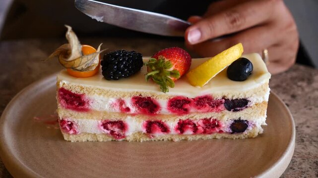 Close up shot of person cutting and eating a delicious and beautiful fruit cake.