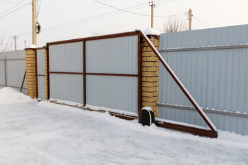 Obraz premium Snow-covered metal gate with brick pillars