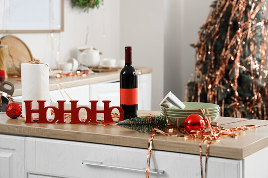Christmas party preparation, red ho ho ho sign with wine bottle and festive decorations on a kitchen counter for holiday celebration and home gathering
