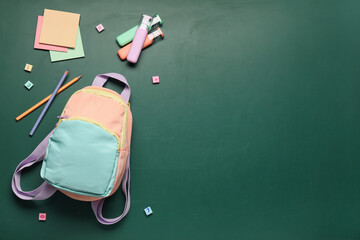 Back to school education concept, colorful backpack with stationery supplies on a green chalkboard background with copy space for student learning © Pixel-Shot