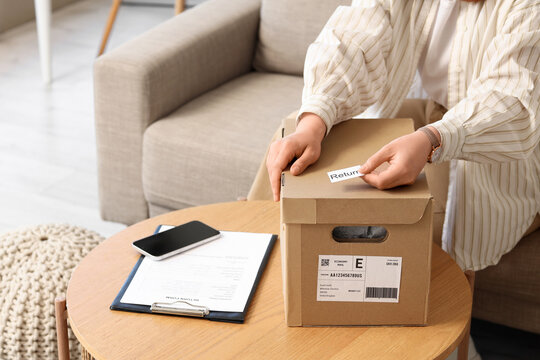 E-commerce return policy and customer service, person preparing a parcel with a return label for shipping from home in a comfortable living room