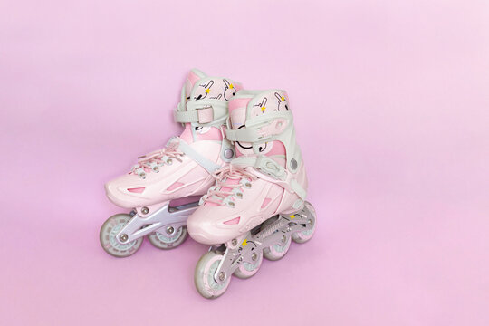 Banner of a pair of pink kid roller skates isolated on a pastel pink background with space for text. Rollerblading and active kid leisure concept. Mockup, copy space