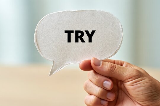 Hand holding paper speech bubble with try word concept motivation sign
