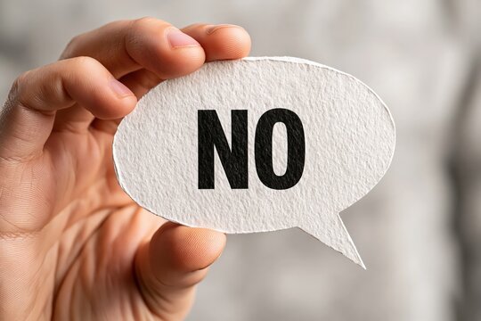 Hand holding paper speech bubble with word no for refusal concept