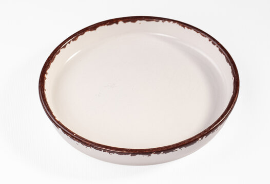 Empty vintage white enamel plate with distressed brown rim isolated on white background for rustic tableware display