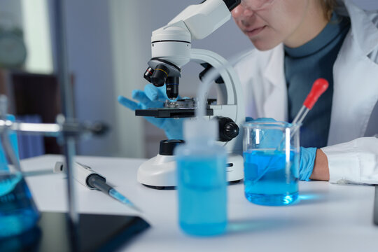 Scientist wearing protective glasses working with microscope in laboratory