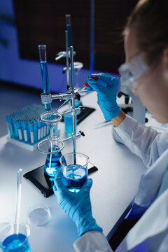 Scientist analyzing liquid in laboratory glassware setup