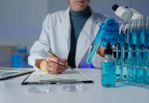 Scientist analyzing liquid samples, writing research data