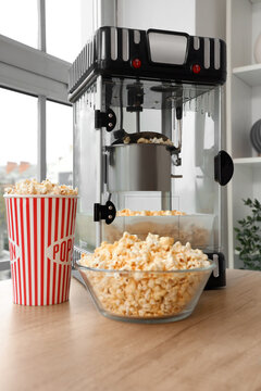 Home cinema and movie night entertainment, popcorn machine with fresh snacks in a striped bucket and glass bowl on a wooden table in a bright room