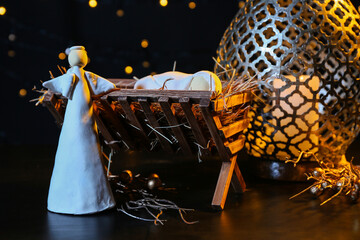 Fototapeta premium Manger with baby, angel and lantern on dark background. Christmas story concept