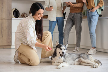 Work-life balance and remote work, woman playing with husky dog in home office while colleagues collaborate in background during casual team meeting © Pixel-Shot